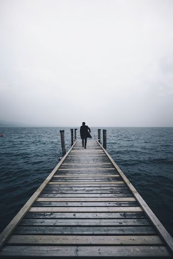 man walking on dock surrounded by ocean during daytime