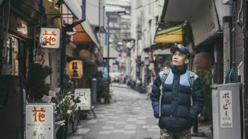 Man Walking on Grey Concrete Alley Surrounded by Buildings