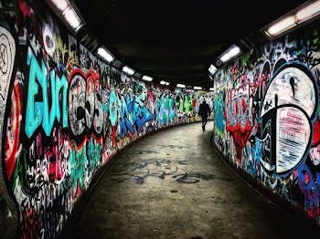man walking on hallway with graffiti walls
