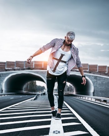man walking on rail in the middle of the road near tunnel