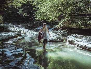Man Walking on River in Between Stone and Tree
