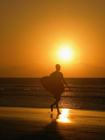 Man Walking on Seashore With Surfboard