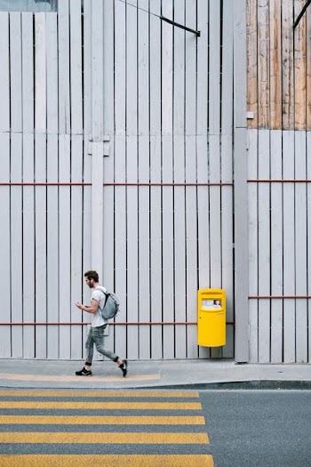 man walking on sidewalk beside pedestrian lane at daytime