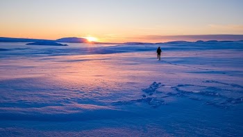 man walking on snowfield during sun rise