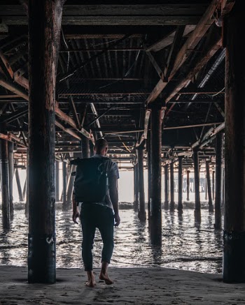 Man walking towards the ocean below the Santa Monica Pier