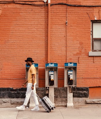 Man Walking With Luggage Near Telephone Booth