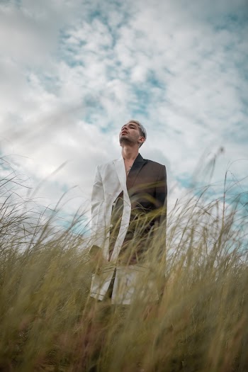 Man Wearing a black and White Suit In A Grassy Area