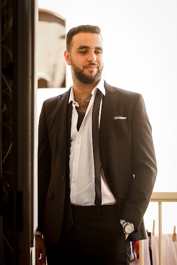 Man wearing a black suit standing beside door