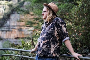 Man Wearing a Brown Hat and eyeglasses Leaning on Fence