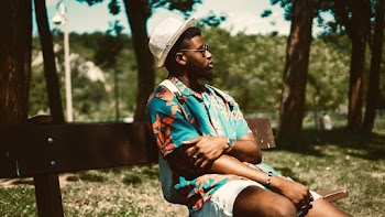 Man Wearing A Floral Shirt While Sitting on a Bench 