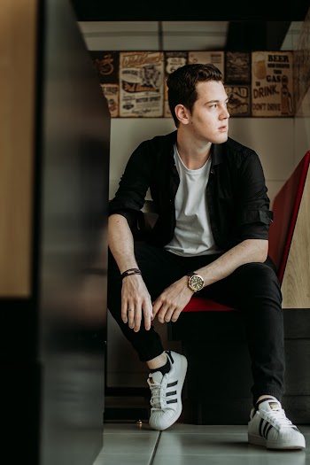 Man Wearing Adidas Superstar While Sitting on Chair