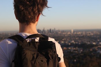 man wearing backpack on high ground