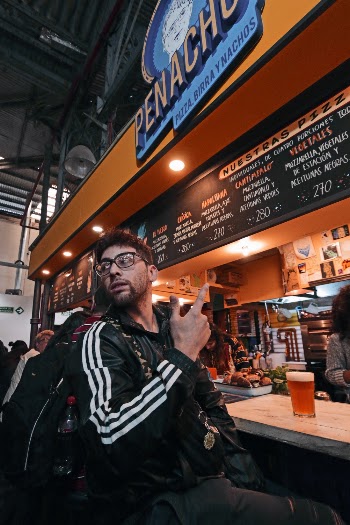 Man Wearing Black and White Jacket and Eyeglasses Sitting by Bar Counter
