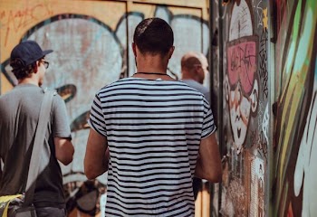man wearing black and white stripe standing near graffiti