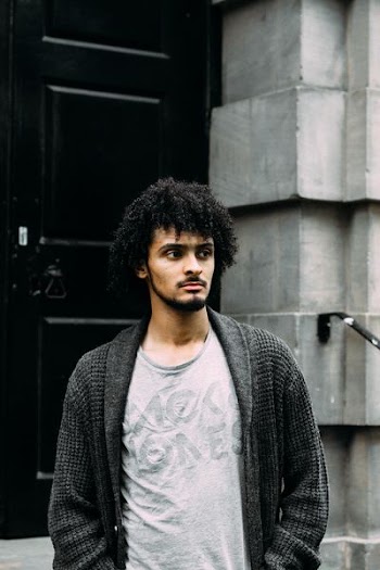 man wearing black cardigan at the back of black door