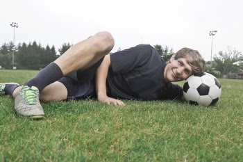 Man Wearing Black Crew-neck Shirt and Black Shorts Lying on Green Grass at Daytime