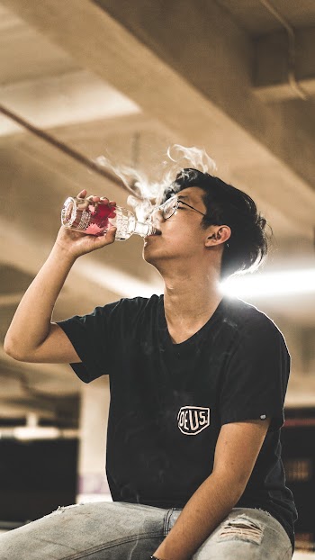 Man Wearing Black Crew-neck Shirt Drinking on Glass Bottle