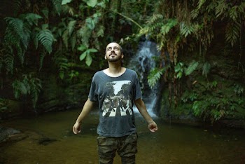 Man Wearing Black Crew-neck T-shirt and Brown Bottoms Standing Near Stream of Water