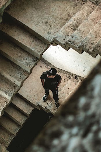 Man Wearing Black Crew-neck T-shirt Standing on Concrete Stairs