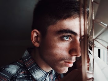 Man Wearing Black, Gray, and Red Plaid Collared Top Staring Outside Window