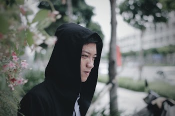 Man Wearing Black Hoodie Jacket Standing Near Pink Flowers