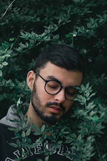 Man Wearing Black Hoodie Surrounded by Green Leafed Plant