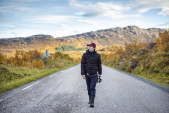 Man Wearing Black Jacket and Black Pants Walking on Road
