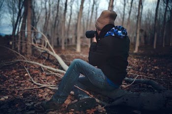 Man Wearing Black Jacket and Blue Jeans Sitting on Tree Branch