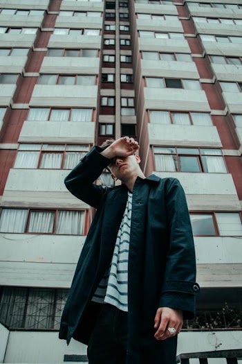 man wearing black jacket standing near building