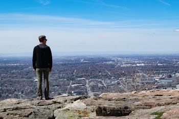 Man Wearing Black Jacket Standing on Rock Monolith