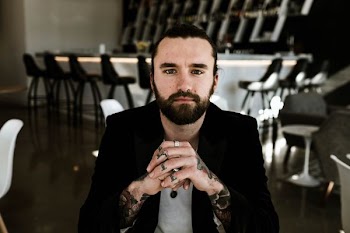 man wearing black jacket with hands clasped infront