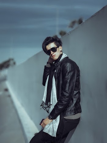 Man Wearing Black Leather Jacket and Sunglasses Standing and Leaning on White Painted Wall