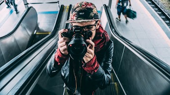 Man Wearing Black Leather Zip Up Jacket and Dslr Camera