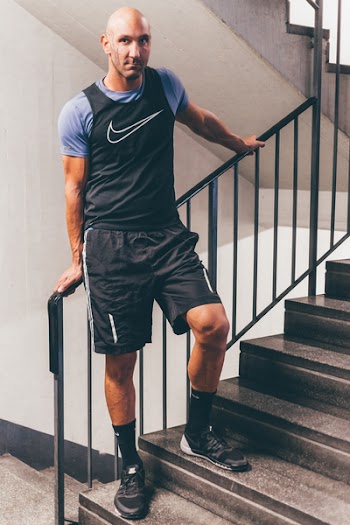 Man Wearing Black Nike Tank Top Placing His Hands on Black Stair Handrail