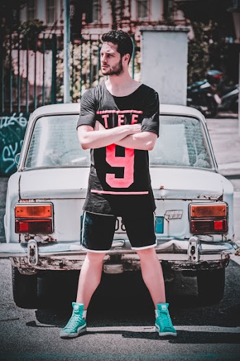 Man Wearing Black Scoop-neck T-shirt and Black Gym Shorts Standing Behind White Vehicle