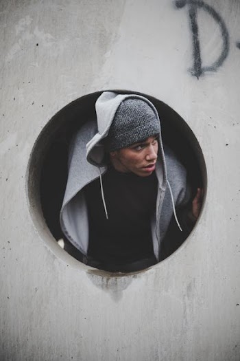 man wearing black shirt and knit cap with hoodie jacket inside concrete hole