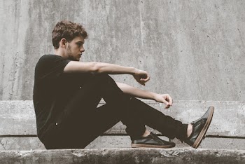 Man Wearing Black Shirt and Pants Sitting on Bench
