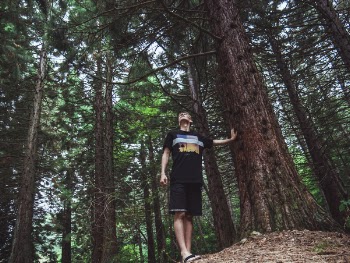 Man Wearing Black Shirt Touches Tree Trnk