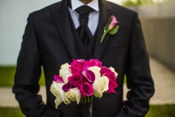 Man Wearing Black Suit With A Corsage Holding Bouquet Of Flowers