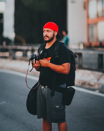 Man Wearing Black  T-Shirt and Red Cap Holding Camera