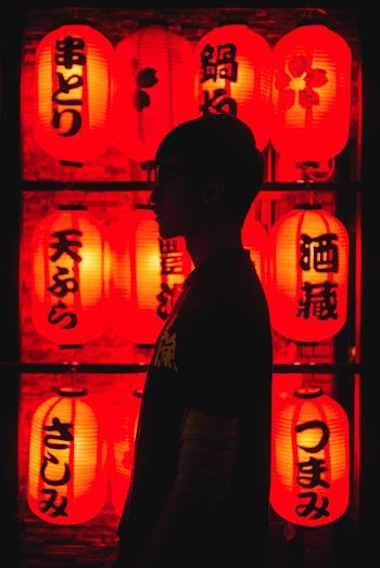 man wearing black t-shirt in front of paper lamps