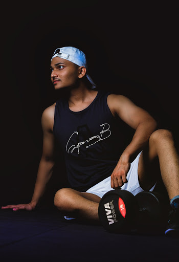 Man Wearing Black Tank Top Sitting on Black Suface