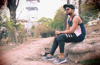 Man Wearing Black Tank Top Sitting on Gray Stone