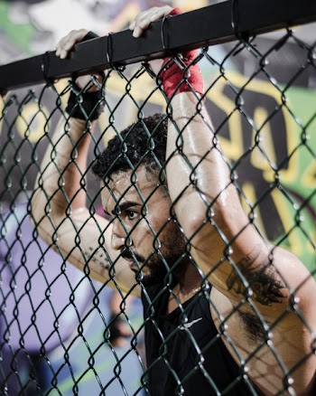Man Wearing Black Tank Top While Holding Fence