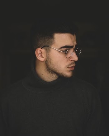 man wearing black turtleneck top and silver framed eyeglasses