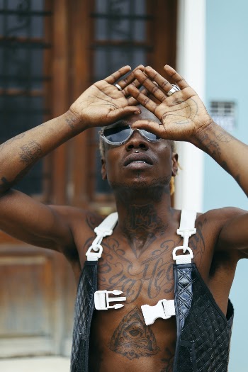 Man Wearing Black Vest Covered in Tatoos Covering his face with his Hands