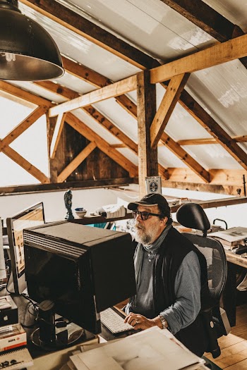 Man Wearing Black Vest Sitting On Rolling Chair Using Computer