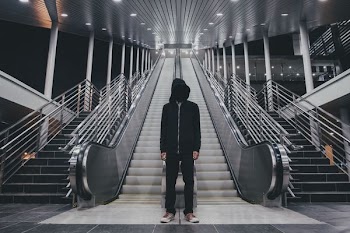 man wearing black zip-up hoodie standing near stair