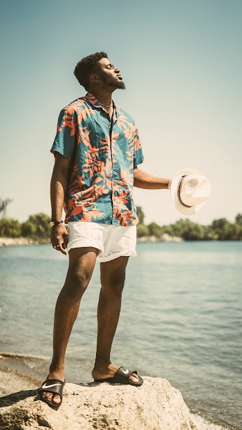Man Wearing Blue and Orange Floral Top Standing on Rock