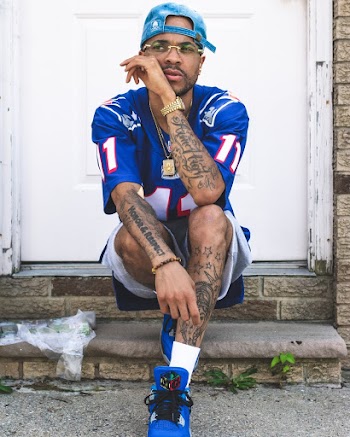 Man Wearing Blue and White Jersey and Blue Cap Sitting Beside White Door